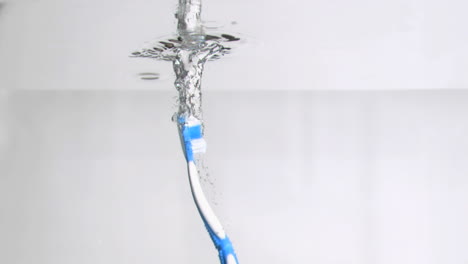 one blue toothbrush in a super slow motion vertically falling in water