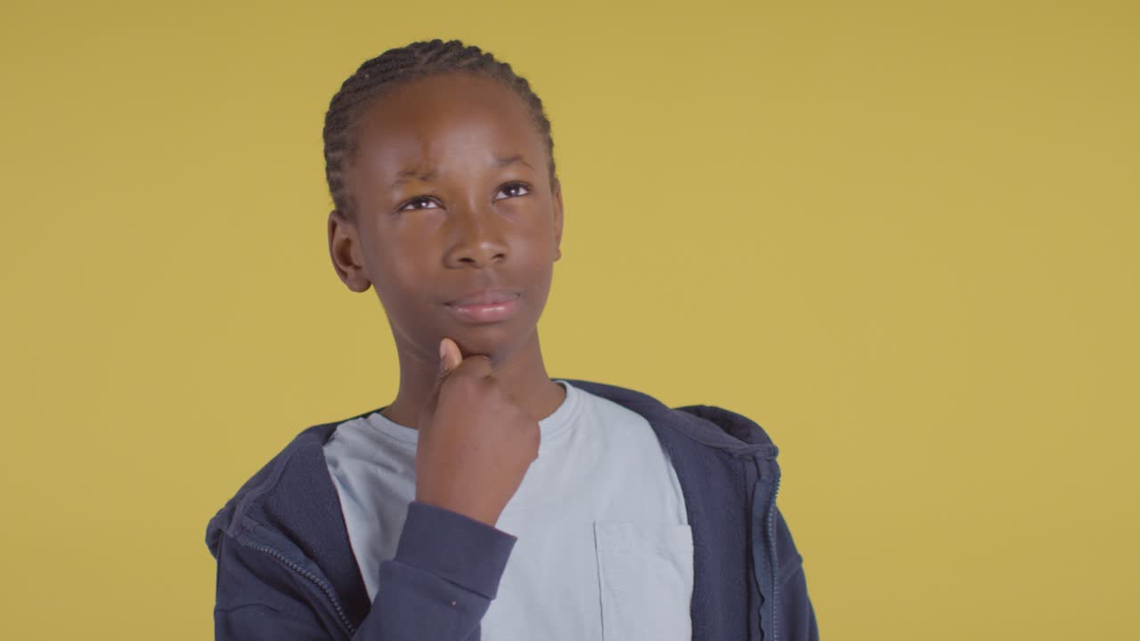 Studio Portrait Of Young Boy Thinking Against Yellow Background 2
