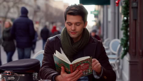 man reading a book at an outdoor cafe