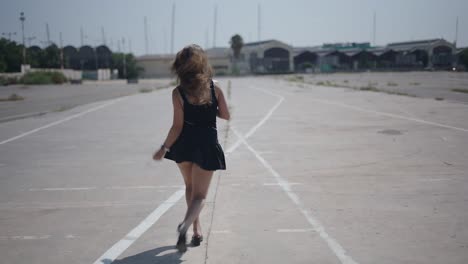 young woman in black dress on empty parking lot