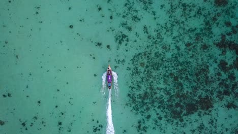 Vista-De-4k-Desde-Arriba,-Vista-Aérea-Impresionante-De-Un-Bote-Tradicional-De-Cola-Larga-Que-Navega-En-Un-Hermoso-Mar-Turquesa-Y-Claro,-Islas-Phi-Phi,-Tailandia