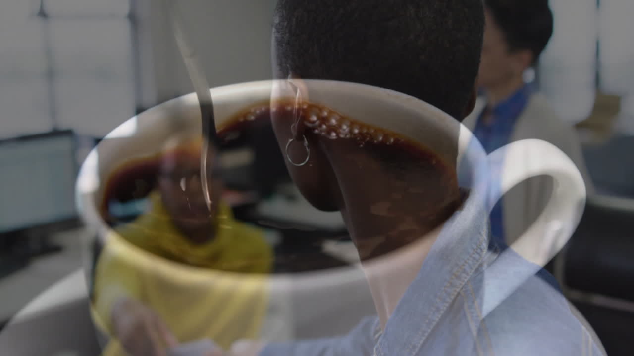 Man stirring coffee mug at office desk, with animated business charts floating over monitors