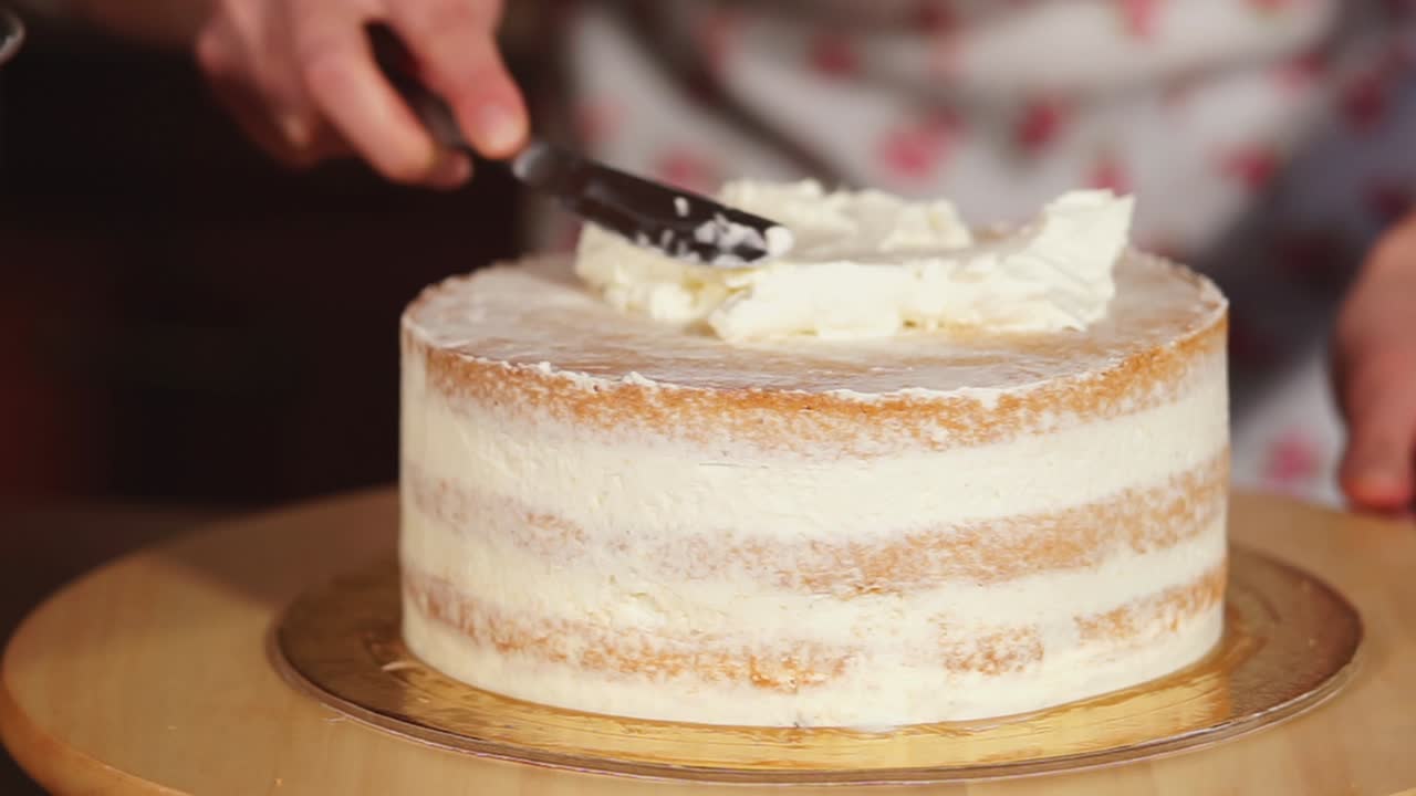 Donna che decora una torta a strati con crema al burro