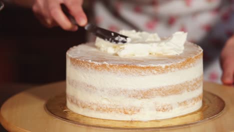 woman decorating a layer cake with buttercream