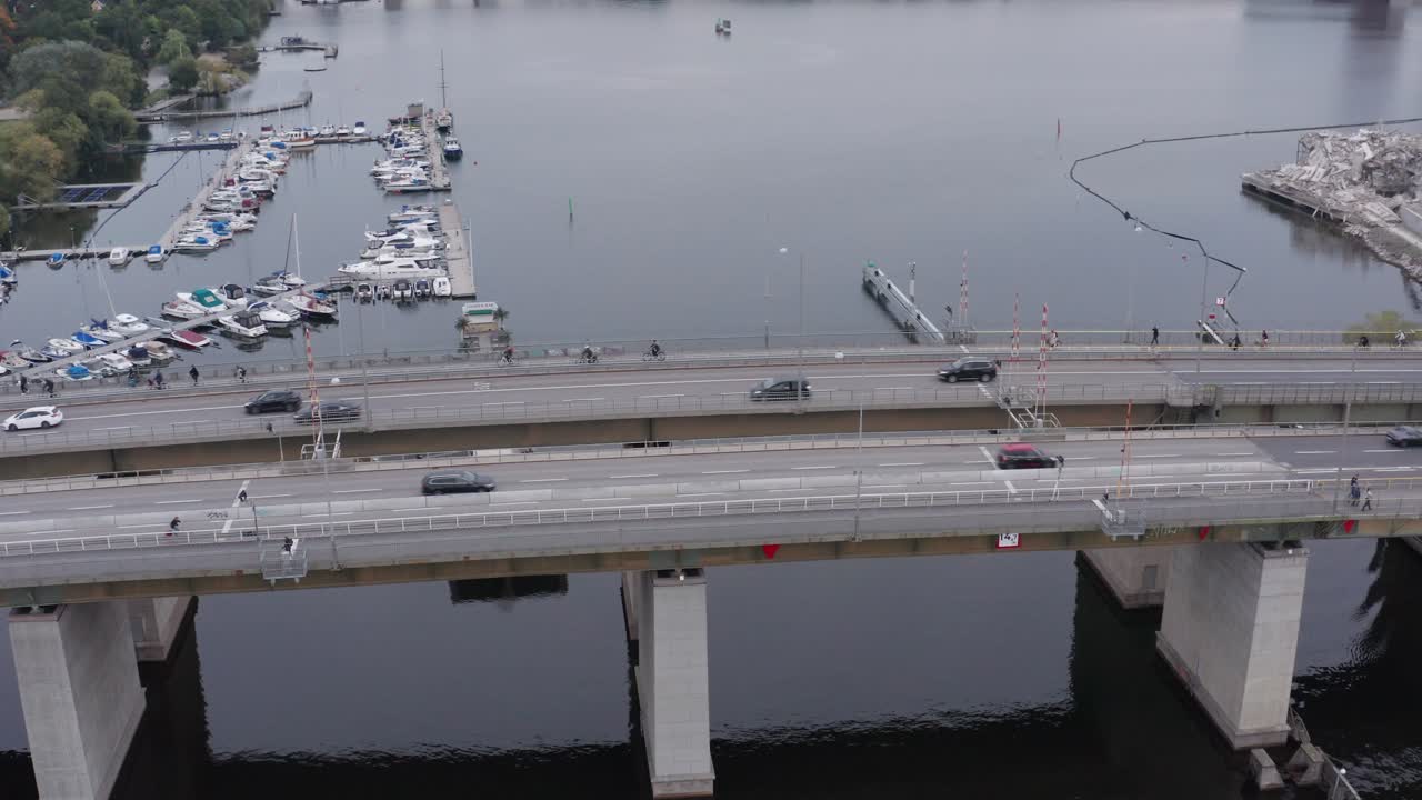 Drone shot orbiting traffic and bikers passing on Liljeholmsbron over water towards Liljeholmen and Hornstull, S&ouml;der, Stockholm