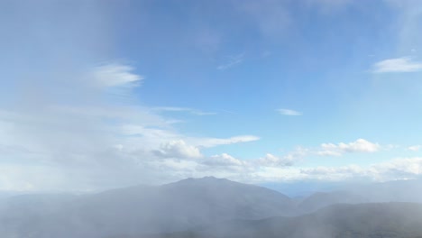 Drone-Pasando-A-Través-De-Las-Nubes-En-El-Cielo-Azul-Sobre-La-Meseta-Verde-De-Prat-D&#39;albis,-Pirineos-En-Francia