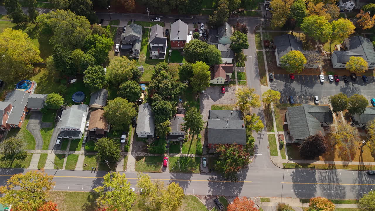 Aerial view of suburban residential neighborhood in USA with homes, streets, parked cars and colorful autumn trees on sunny day