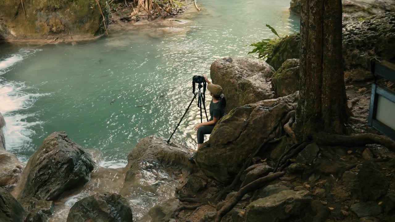 fotógrafo con una cámara dslr en un trípode junto a la cascada en el parque nacional de erawan