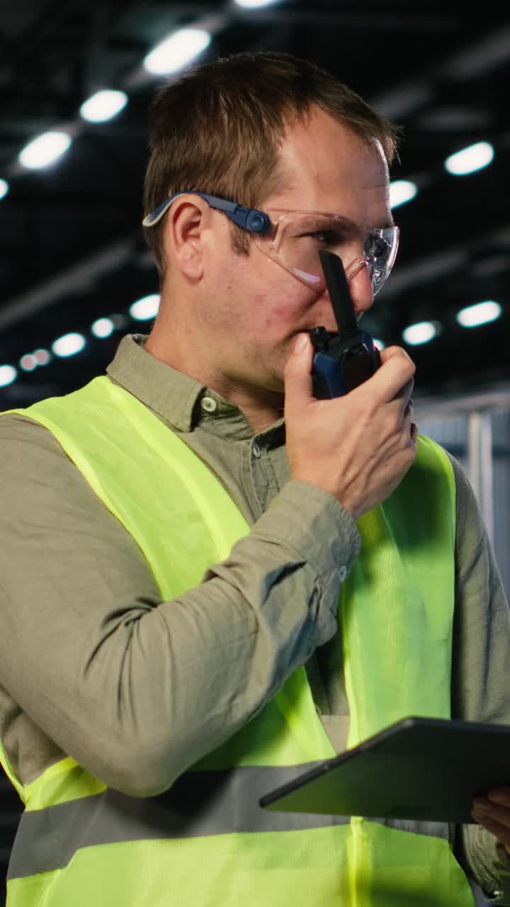 Vertical Video Industrial staff member uses walkie talkie device to coordinate assembly tasks