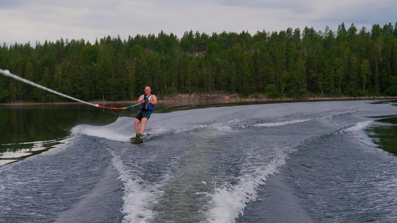 joven montando un wakeboard después de un barco deportivo en el archipiélago sueco en el verano