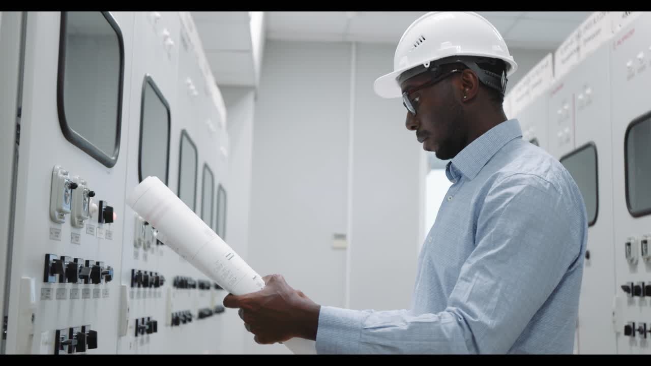 Engineer reviewing plans at a control panel
