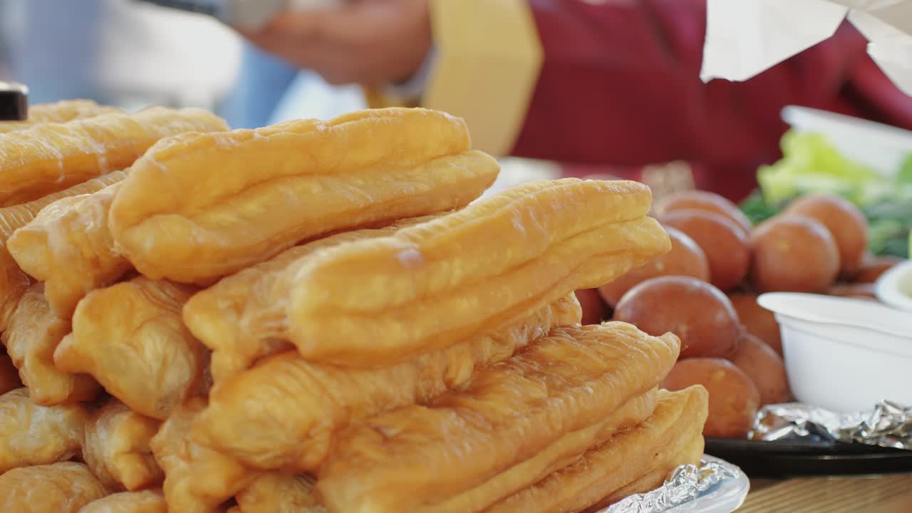 Chinese popular food youtiao close-up. Long golden brown deep fried strip of wheat flour dough,Long golden brown deep fried strip of wheat flour dough, youtiao lightly salted and tearable. Asian breakfast food. Local street food market. High quality 4k footage