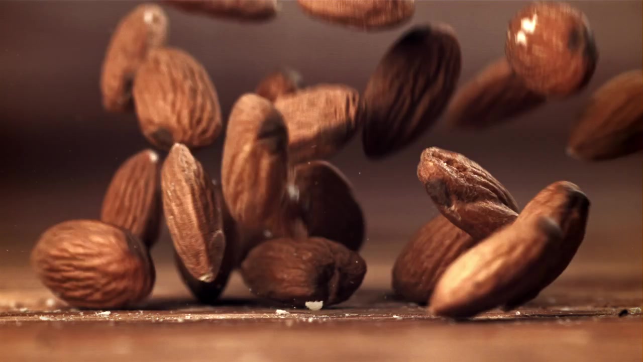 Slow Motion Close-Up of Almonds Falling onto a Wooden Surface
