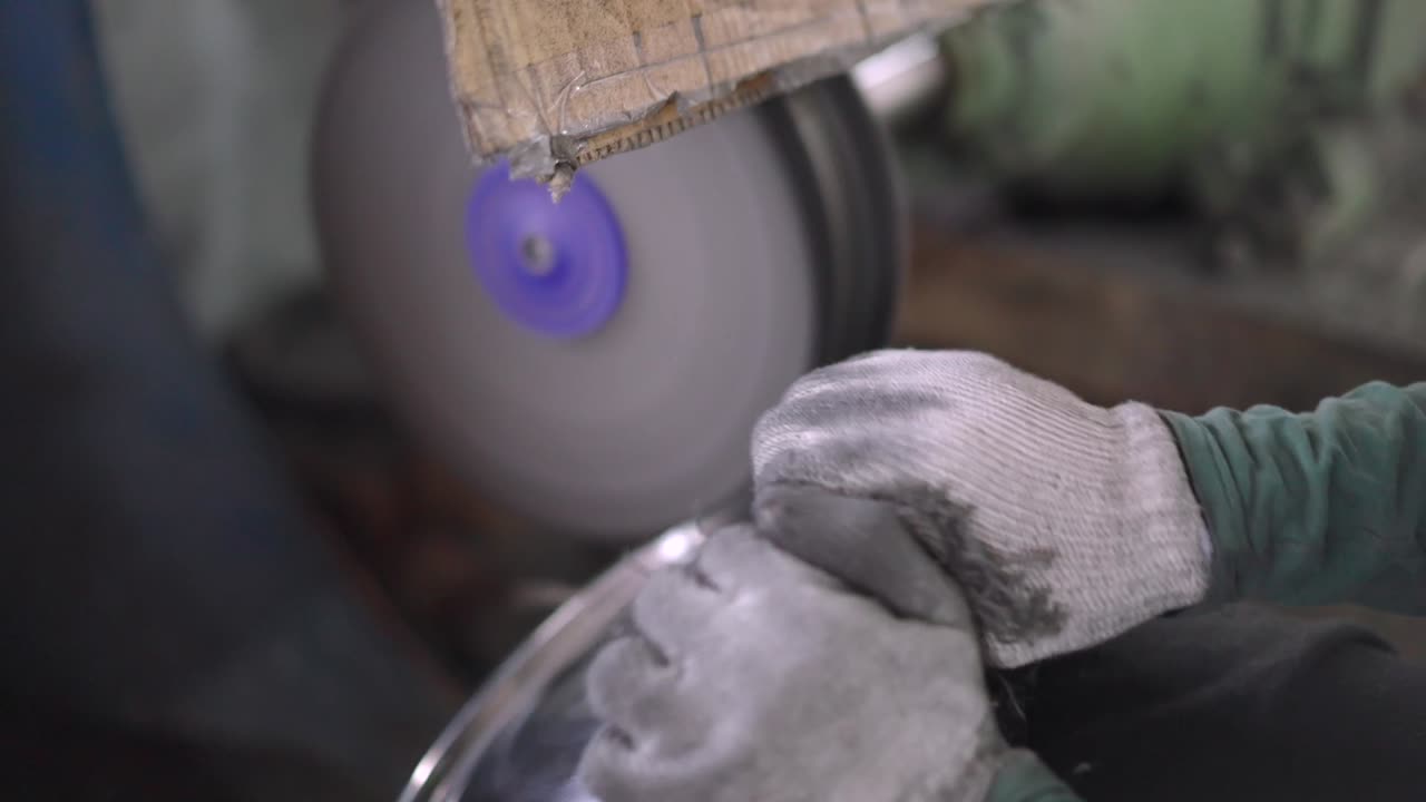 Using a belt sander to produce steel pan cookware in a factory