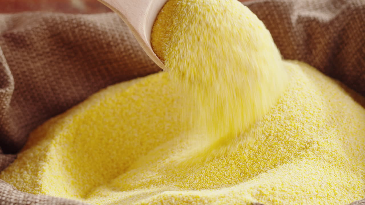 Cornmeal being poured and scooped from a sack