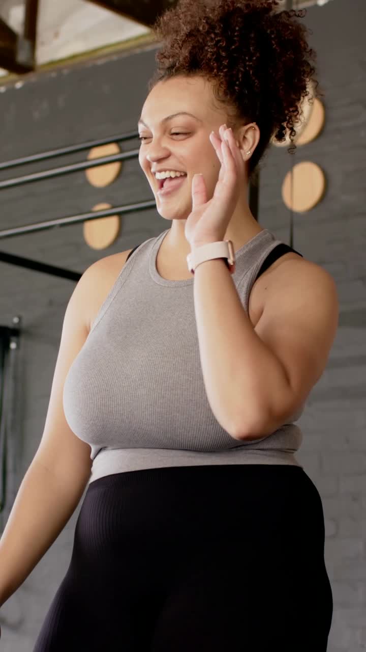 Video verticale: Coach in top grigio che assiste e guida un cliente che inizia un hex curl in palestra, applaudendo.