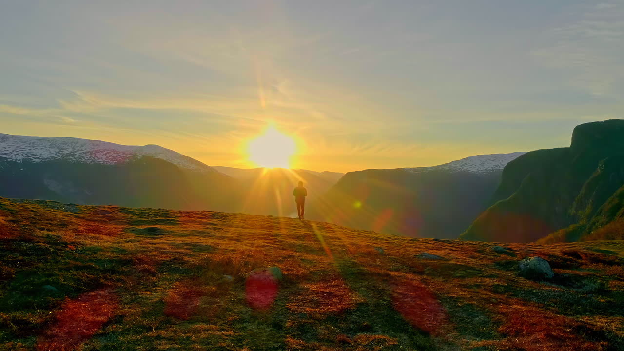 misterioso hombre caminando hacia el sol en la cima de la montaña