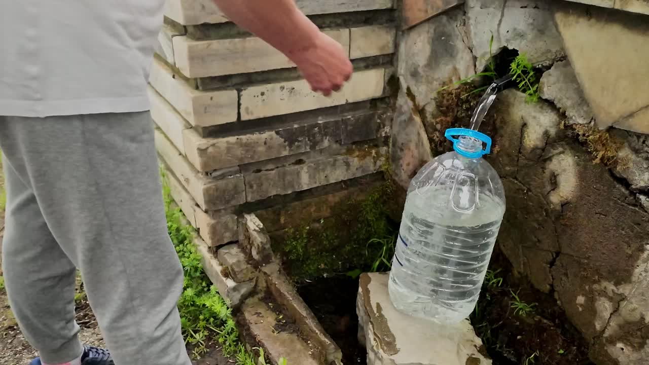 마을 우물 공급에서 무료 자연  광물 물로 병을 채우는 사람