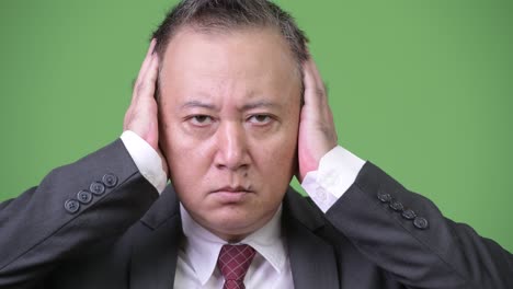 mature japanese businessman covering ears as three wise monkeys concept