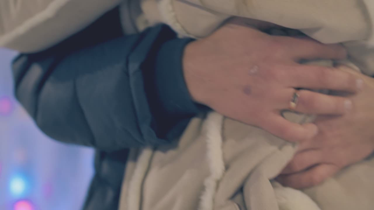 젊은 남자는 저녁 겨울 공원에서 가벼운 재킷을 입고 아내를 껴안습니다.