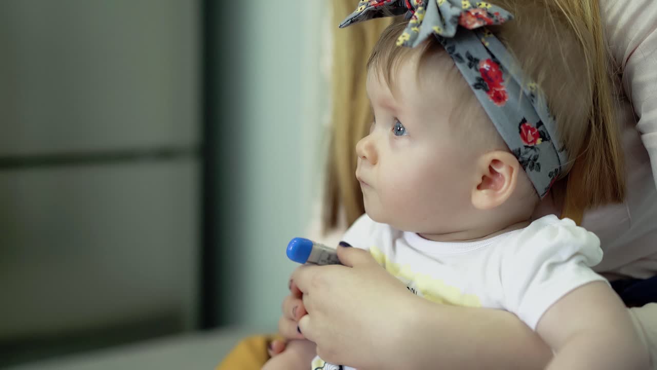 딸은 젊은 어머니의 무 ⁇ 에 앉아 있습니다.