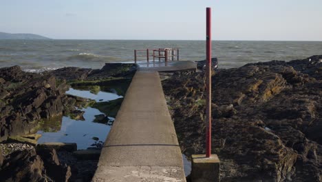 Portmarnock-Beach,-Fingal,-Dublin,-Ireland---Concrete-Platform-Positioned-on-the-Rocky-Shoreline-of-the-Beach---Forward-Shot