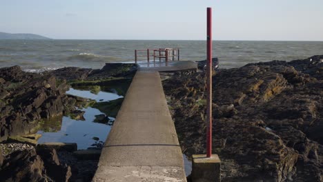 playa de portmarnock, fingal, dublín, irlanda - plataforma de hormigón posicionada en la costa rocosa de la playa - tiro hacia adelante