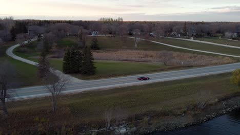 classic red corvette driving down river road