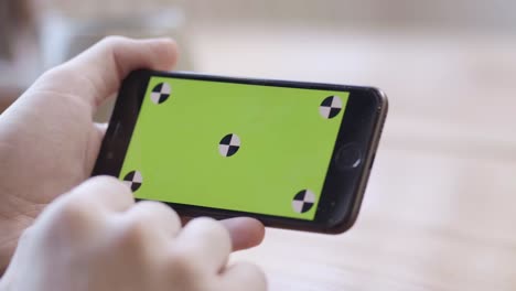 person holding smartphone with green screen for calibration