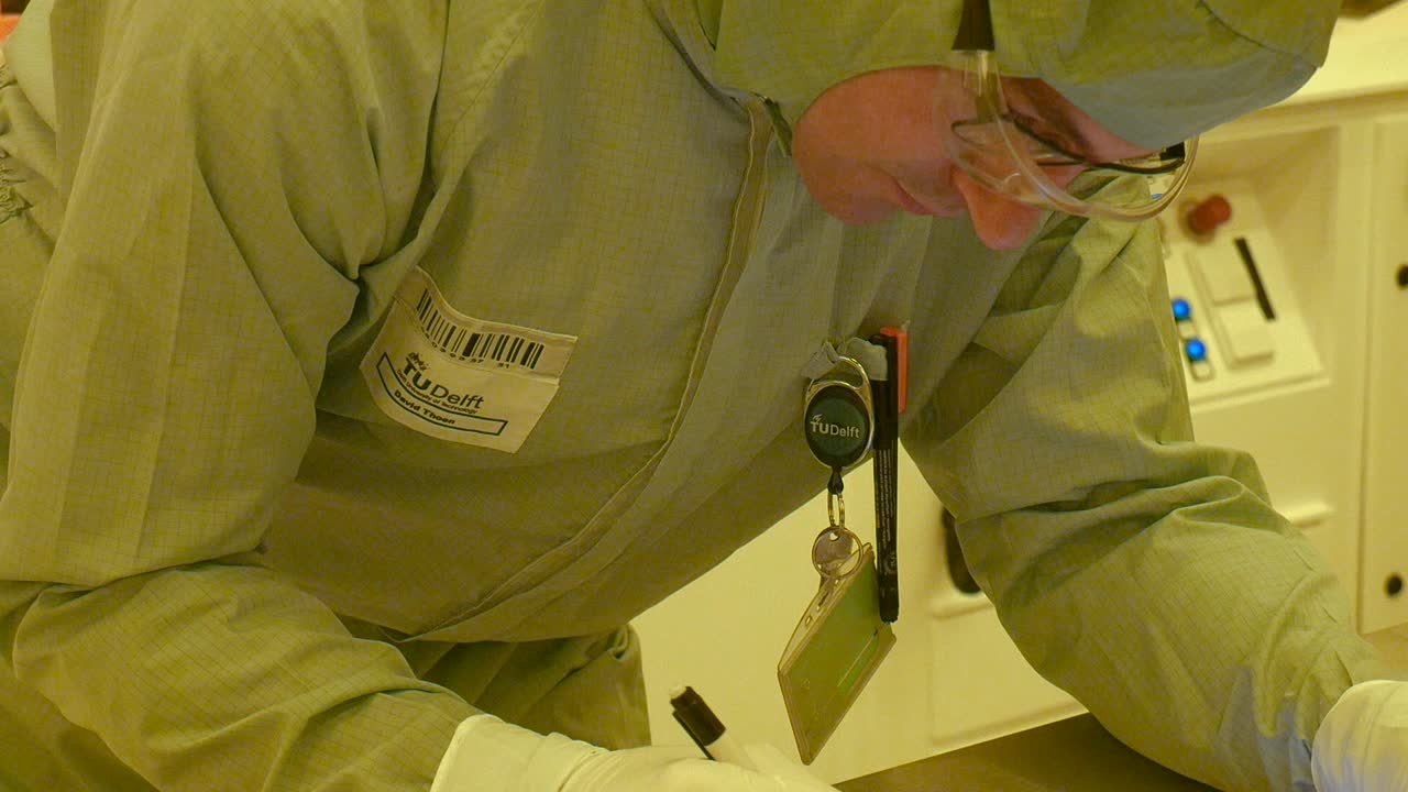 A scientist writing in the clean room about his current experiments or research.