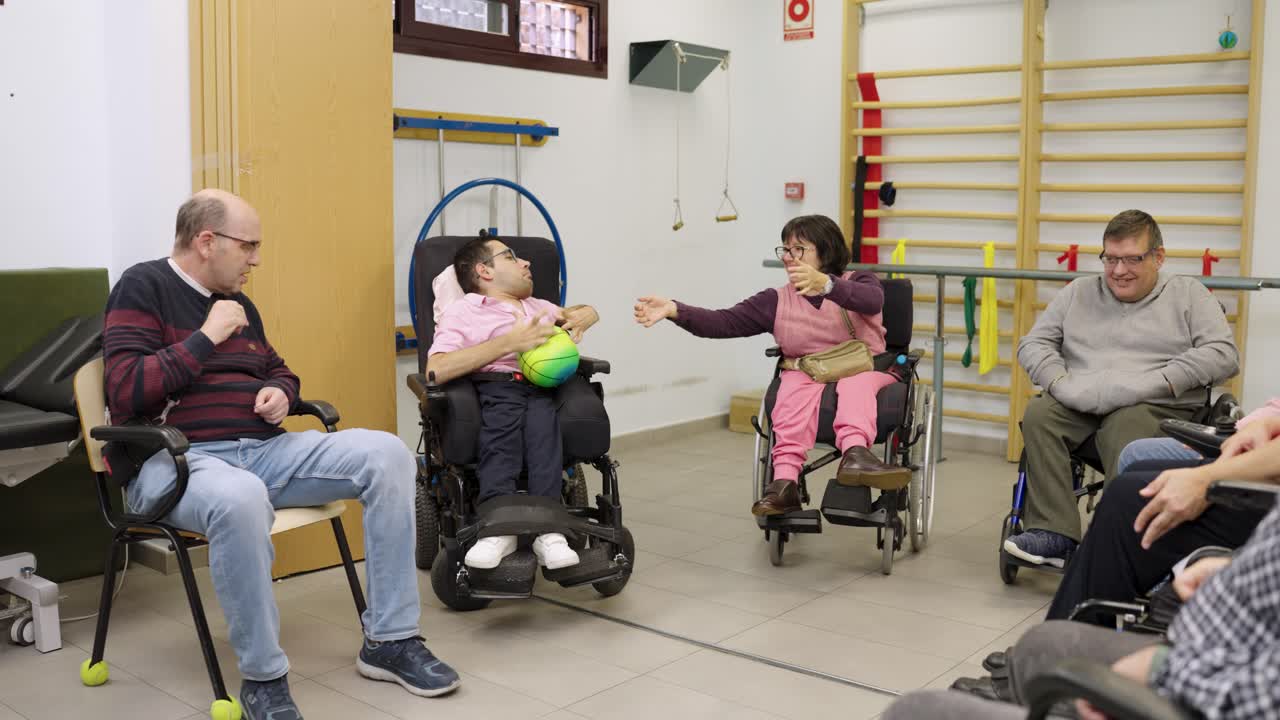 Group of people in wheelchairs playing with a ball during therapy session