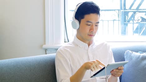 Hombre-Escuchando-Música-En-Una-Tableta-Digital-En-La-Sala-De-Estar-4k