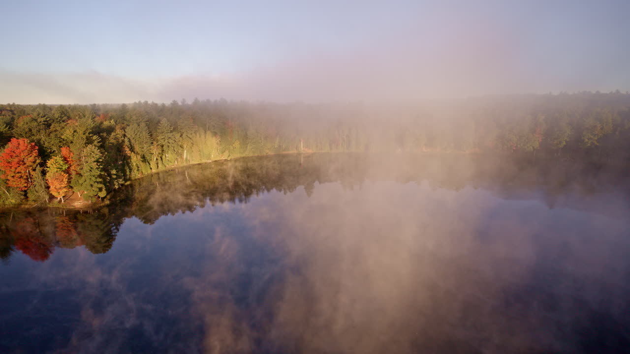 Drone glides over water as morning mist rises into the air