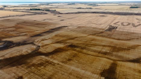 drone panning over a field where the word 'love' is tilled into the stubble