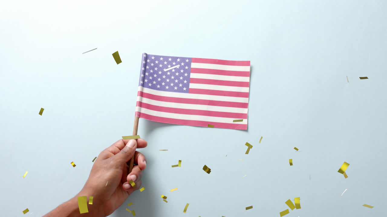 Animazione di coriandoli che cadono su una mano che tiene la bandiera degli Stati Uniti d'America su sfondo blu.