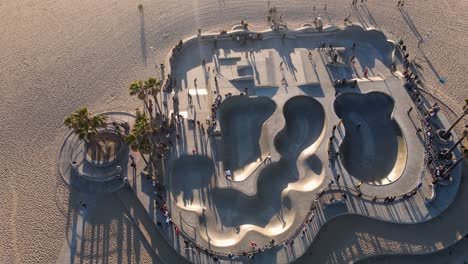 vista aérea de la gente en el parque de patinaje de la playa de venice, puesta de sol en los ángeles, ee.uu. - inclinación hacia arriba, disparo de drones