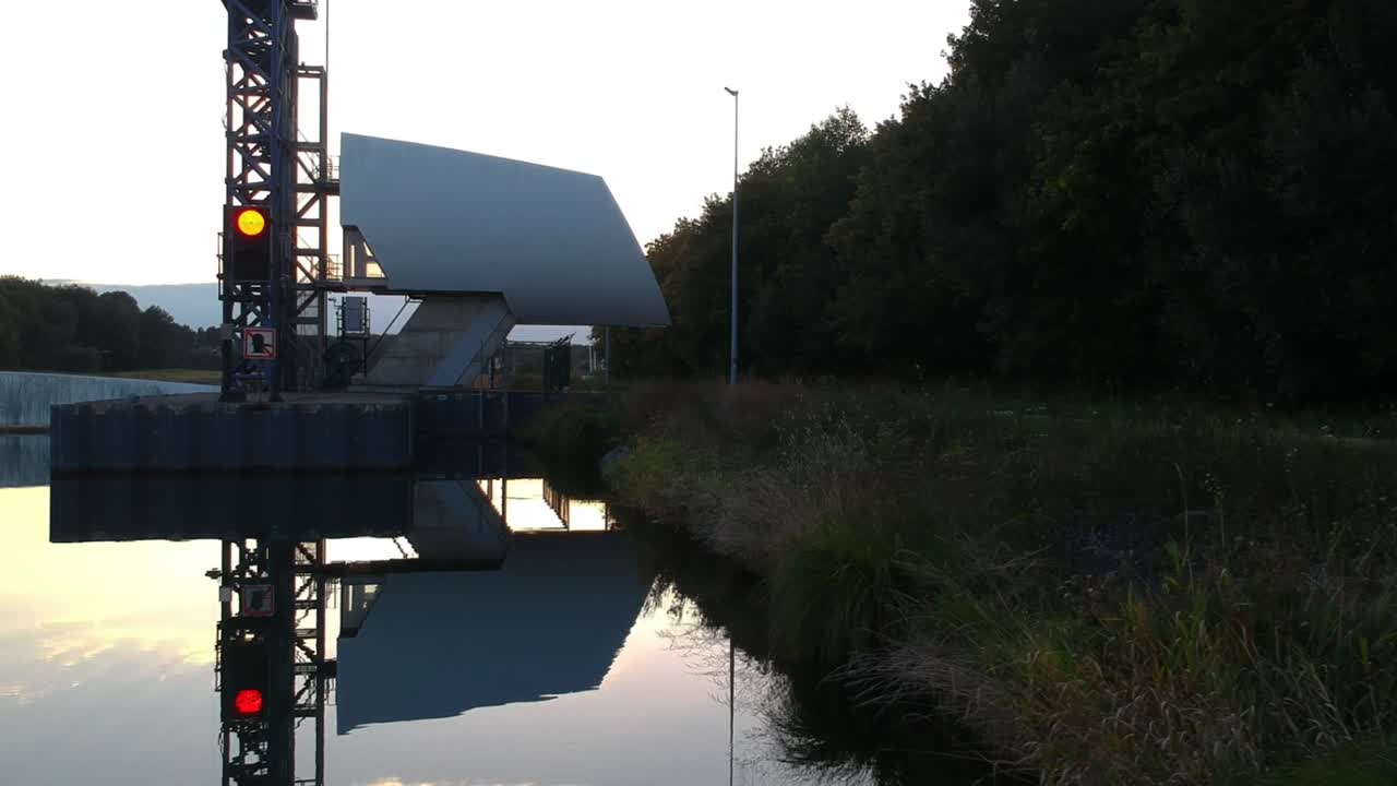 드론은 반사되는 물 위의 망할 금속 구조물 위로 팬을 이동합니다.