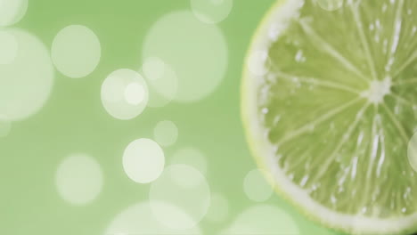 composition of halved lime and white spots on green background