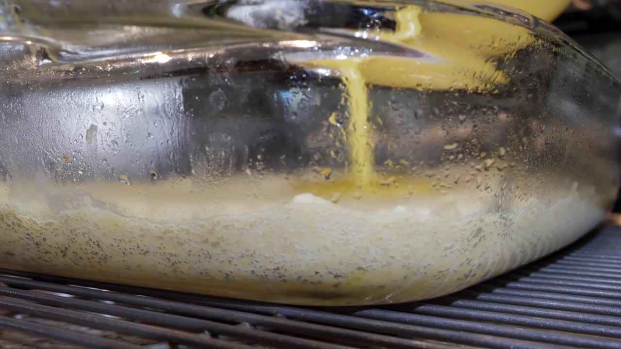 Pouring lemon mix in glass dish over shortbread crust, making lemon bars