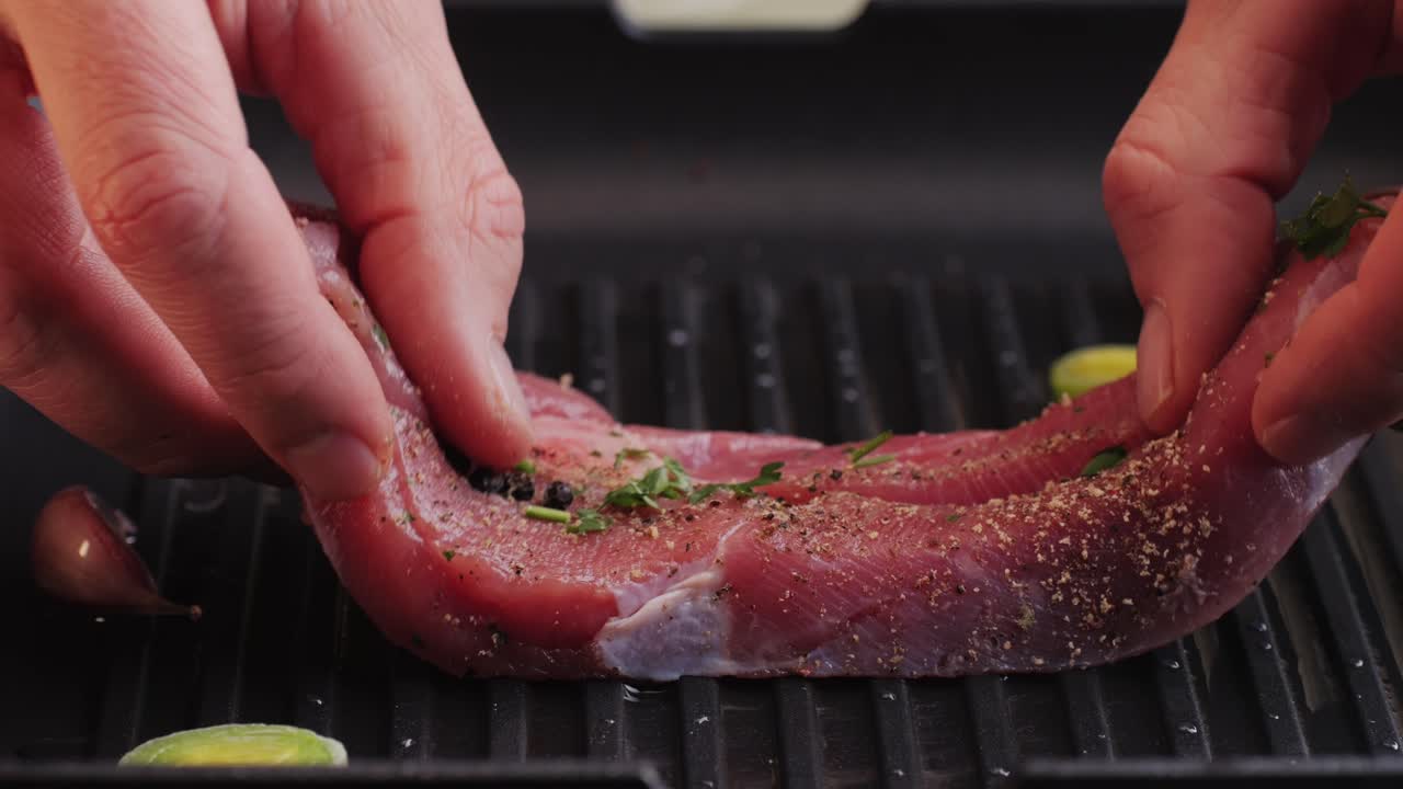 Cooking raw turkey meat in spices with garlic and greens on grill close-up. Fry chicken or turkey slice on frying pan Grilled chicken, duck, turkey kebab with vegetables.