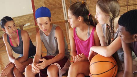 niños de secundaria sentados en un banco en la cancha de baloncesto