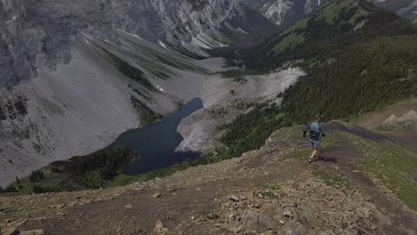 runner on ridge running downhill slipping by lake rockies kananaskis alberta canada