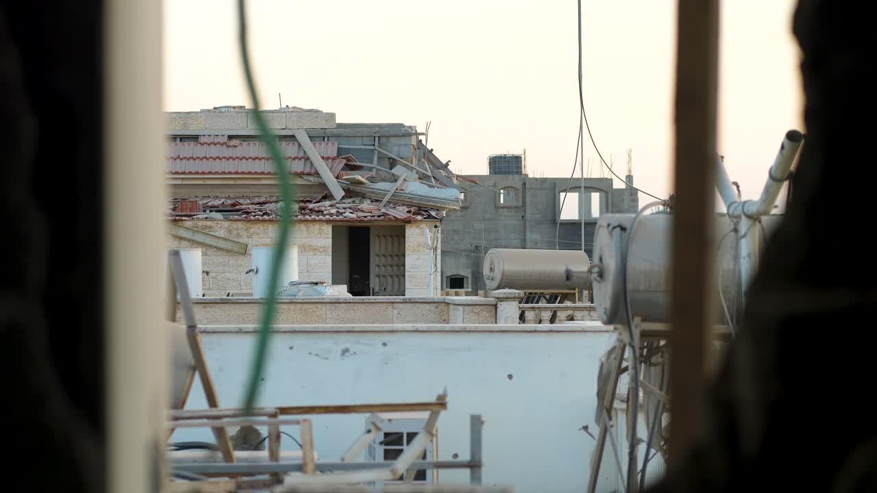 Interior shot showing ruined building through window frame, with pipes and electrical wires - Palestine