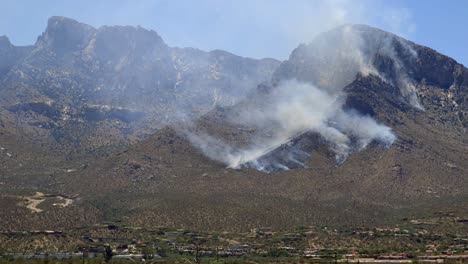 helicopter of firefighters department flying above wildfire smoke on hillside of santa catalina mountains, north of tucson, arizona usa