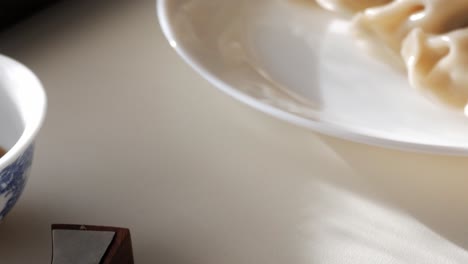 warm light on soy sauce dish, chopsticks, and dumplings out of frame
