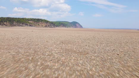 aerial view of the beautiful bay of fundy during low tide with a mountain in the distance during a hot and sunny day located in new brunswick, canada