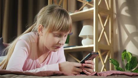 a child rests in his room and uses a smartphone