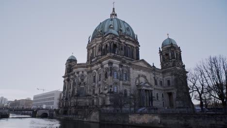 Scenic-water-view-of-Berlin-cathedral-teal-patina-copper-dome-roof-with-Baroque-architecture-and-cement-facade,-Germany,-handheld-pan-up