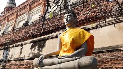 monk draping robe on buddha statue in ayutthaya