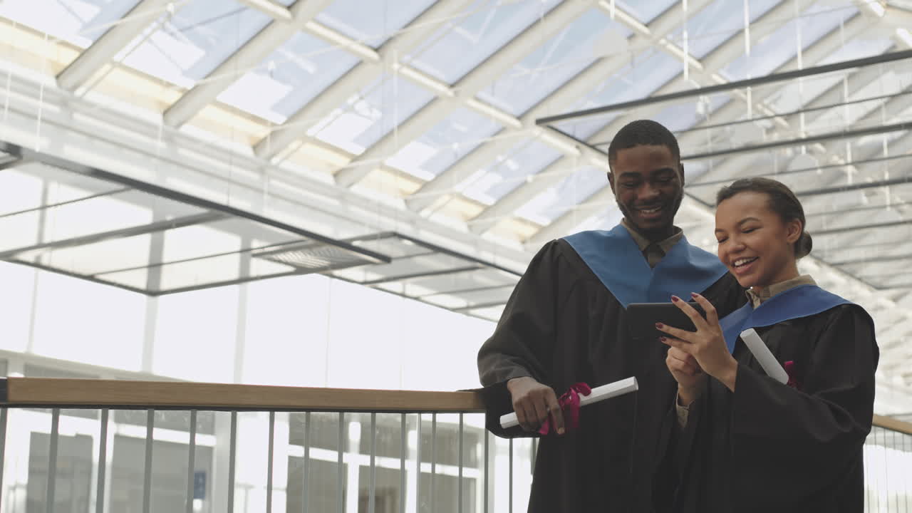 Two African-American Graduates Using Smartphone